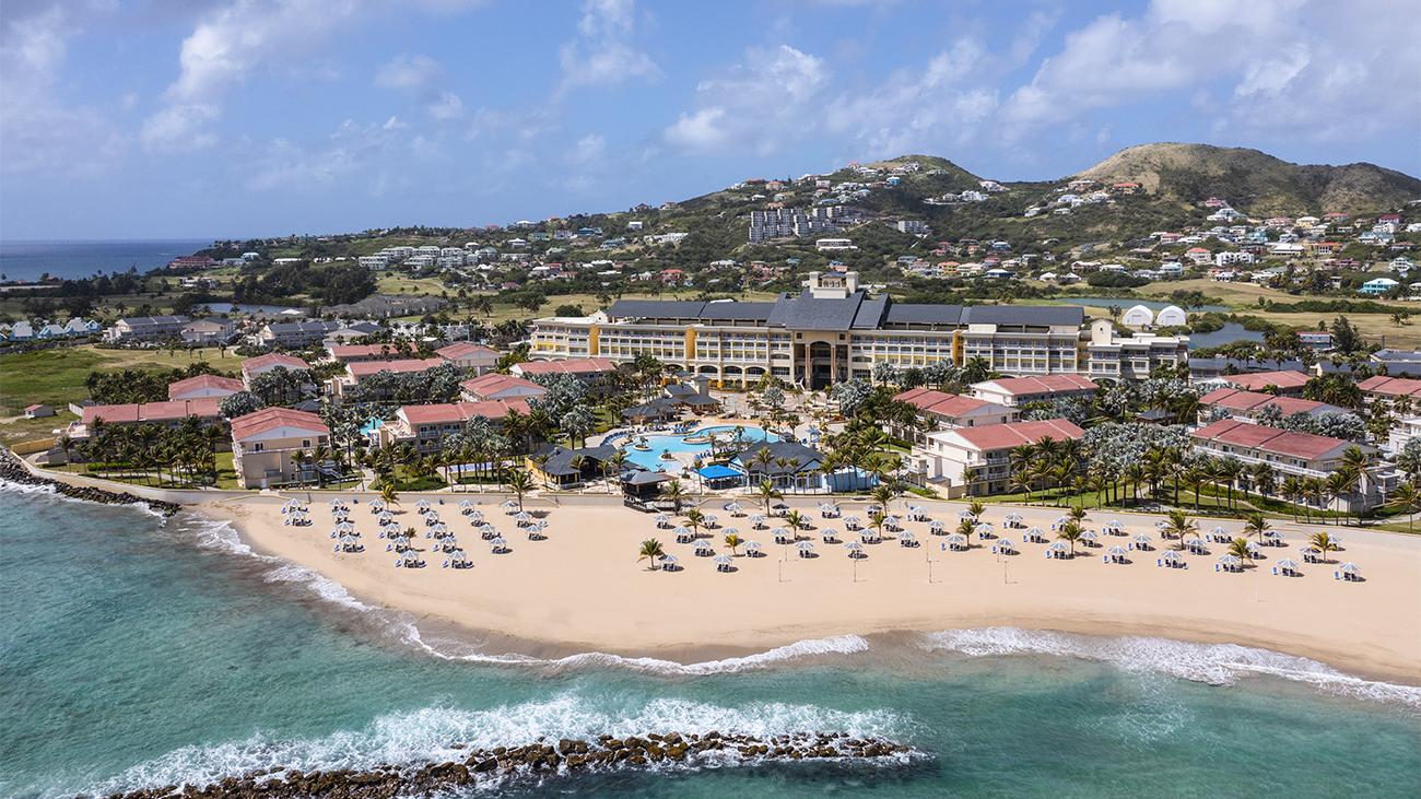Aerial from the sea showing exterior of Marriott's Saint Kitts Beach Club resort timeshare with beach and rock breakwater